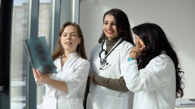 Three women doctors of different races analyze the X-ray