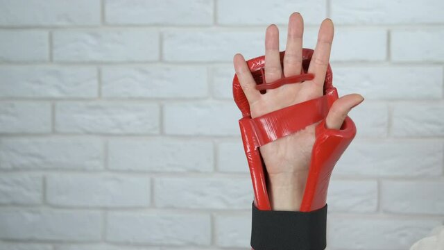 Sport unequality. Female hand with red nails in kickboxing gloves.