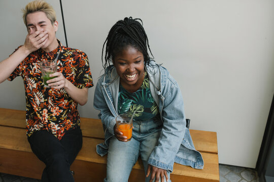 Friends drinking cold pressed juice together laughing