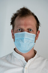 Portrait of a straight man in a white shirt with curly hair and a straight tight look and face mask to protect against covid19, he looks straight