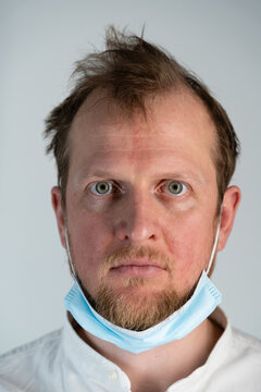 Close-up Portrait Of A Man Where He Is Angry Looking Forward And His Hair Is Drilled, But The Covid19 Protective Mask Is Pulled Under The Chin