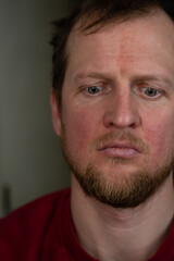 Obraz premium a close up portrait of a man in a red sweater and a disturbed facial expression and a desperate look