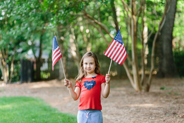 Beautiful young girl holding two flags of the united states
