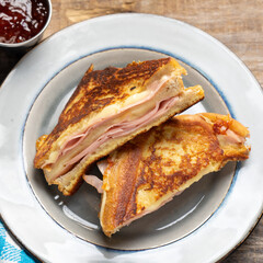 Ham and melted cheese sandwich called Monte Cristo on wooden background