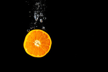 Fototapeta na wymiar Orange falling in water with bubbles