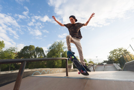 Male skater jumping on ramp railing outdoor in skate park