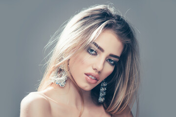 Fototapeta premium Fashion woman, portrait closeup. Jewelry shop and accessory. Earrings on sexy blonde woman, copy space.
