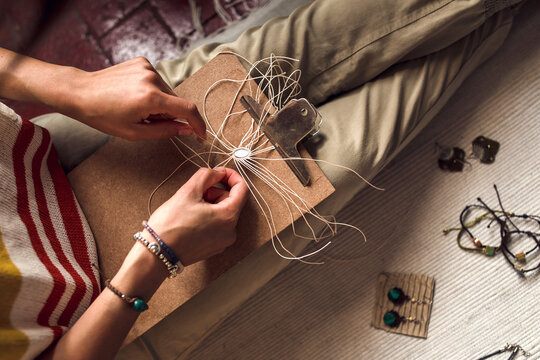 Woman's hands weaving macrame jewelry