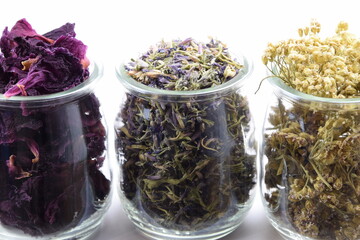 Glass jars with peony petals, hyssop flowers and yarrow flowers, dried herbs flowers on white background