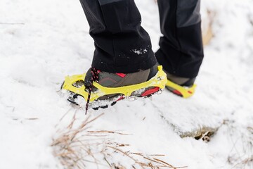 Woman hiking in the snowy mountains. A close-up of crampons on shoes.