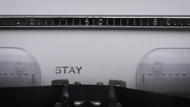 Typing text STAY HOME on vintage manual typewriter. Close up of writes word on white paper. Shot in macro 4K resolution. Concept of COVID-19 or CORONOVIRUS.
