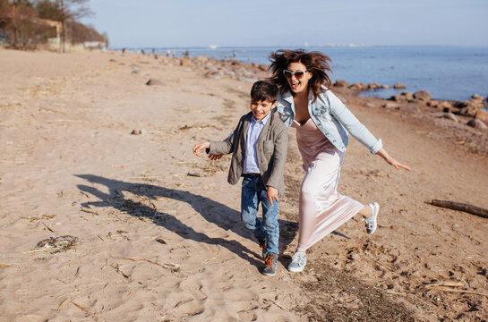 Mother and son running and playing at the beach near the sea