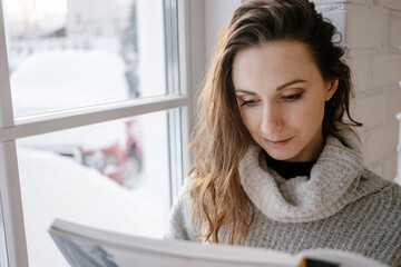 girl reading book sitting in bedroom