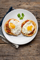 Fried eggs with sauce and tortilla called rancheros for  breakfast on wooden background. Mexican food