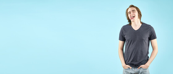 Portrait of an emotional young man in a T shirt posing for the camera isolated on a blue background