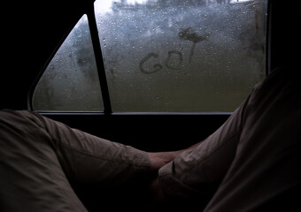 Anonymous traveler against car window with message