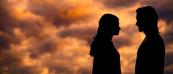 The silhouette of a young couple loving each other on the background of the sunset. A couple in...