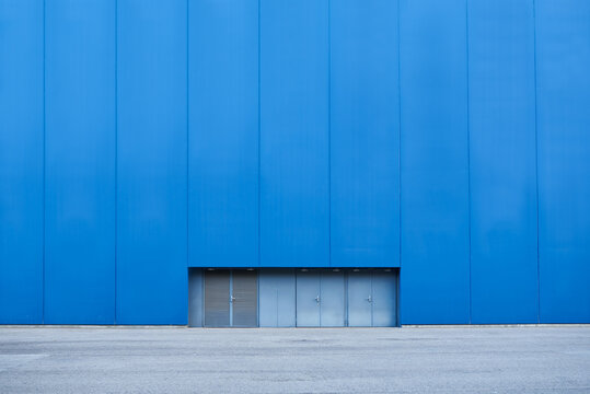 Bright blue wall of industrial building with windows in basement