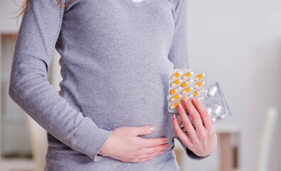 Obraz premium Pregnant woman taking pills during pregnancy
