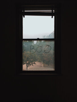 Boo written on a dirty window in an abandoned building
