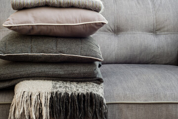 grey sofa with cushions and blankets pile up