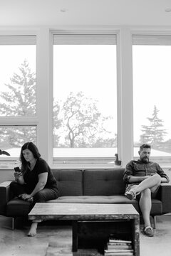 Unhappy couple at home on couch using phones