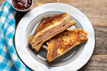 Ham and melted cheese sandwich called Monte Cristo on wooden background