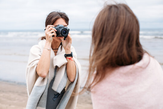 Two girls friends are having fun on the beach together, making photos, doing selfi