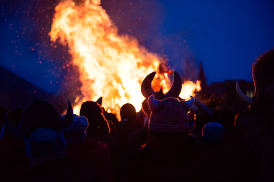 People wearing viking hats around a large bonfire at night