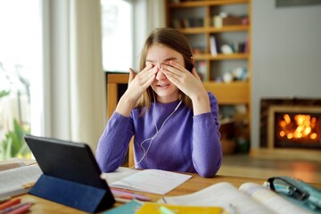 Preteen schoolgirl doing her homework with digital tablet at home. Child using gadgets to study. Education and distance learning for kids. Homeschooling during quarantine.