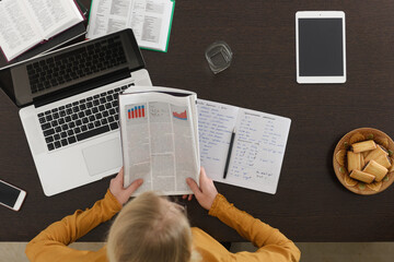 Woman reading newspaper at desk