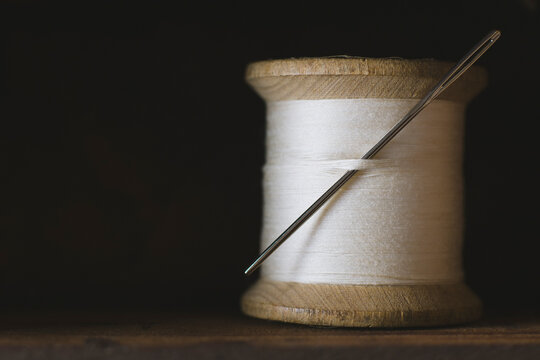 Spool of white cotton thread with needle