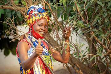 A smiling beautiful African female farmer with red nose mask giving thumbs up 