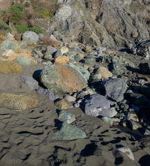 Large, colorful rocks on Northern California beach with dark sand