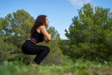 Naklejka na ściany i meble Girl does squats on a park in the middle of the woods in Palma de Mallorca (Spain)