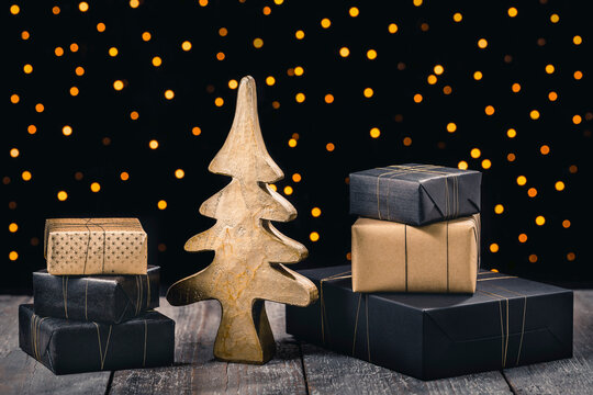 Mini golden christmas tree surrounded by gifts and christmas lig