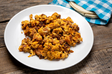 Scrambled eggs with chorizo for breakfast on wooden background. Mexican  food