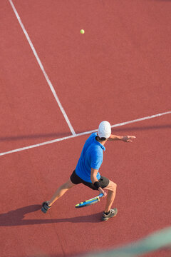 View from above of man playing tennis on slag court