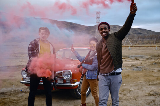 Cheerful friends with smoke grenades