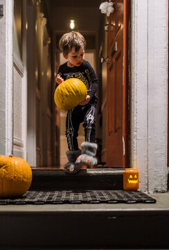 Boy with pumpking on doorstep