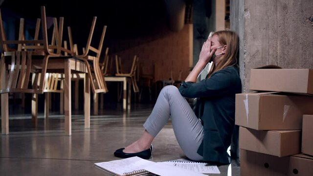 Tired owner sitting on floor in closed cafe, small business lockdown due to coronavirus.