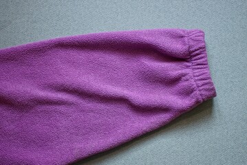 one long lilac sleeve of a woolen sweater lies on a gray table