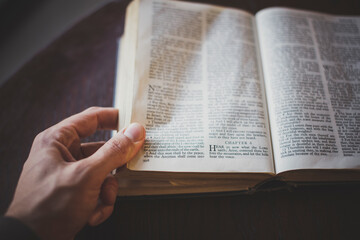 Close up of hand turning pages of the Bible