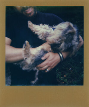 Polaroid gold frame scan of a man making a fuss of a small terrier dog