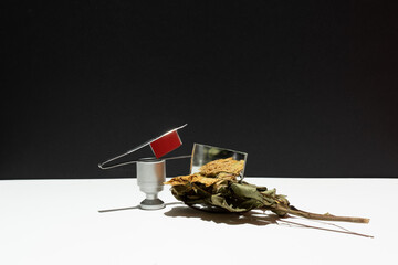 Abstract yellow dried flower beside vase over mirror besides red glass. Set desgin. Over simple geometric black white background.