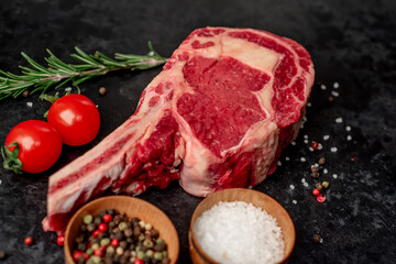 Raw cowboy steak with spices on stone background 