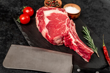 Raw cowboy steak with spices on stone background