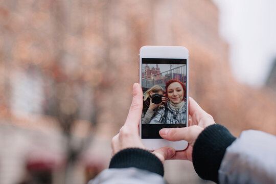 Two girlfriends selfie on phone - one of the girls is photographer