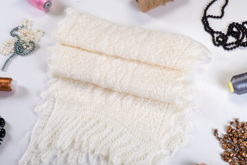 flat lay closeup on handmade white woolen scarf with diferent accessories