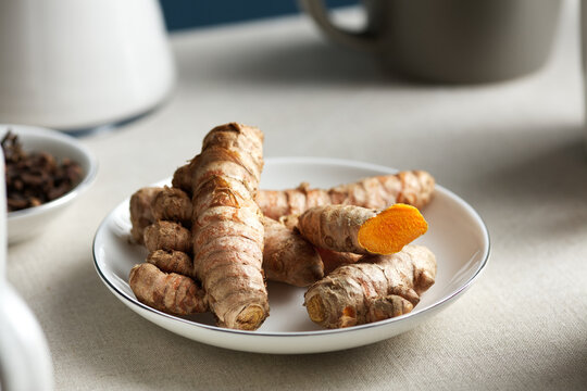 Turmeric root on saucers in close-up.